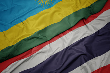 waving colorful flag of thailand and national flag of rwanda.