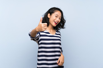 Asian young woman over isolated blue background with thumbs up because something good has happened