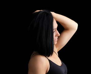 Fototapeta na wymiar Adult girl with a sports figure in black bra standing on a dark background