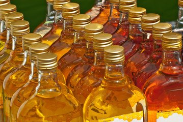 Various bottles of alcoholic beverages are sold at the fair. Tinctures on home-made herbs. Natural drinks in jars on the shelf.