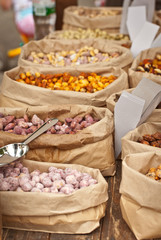 Many different nuts are sold at the fair. Nuts are sorted into paper bags.