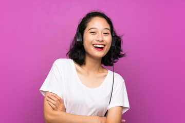 Fototapeta premium Asian young girl listening music with a mobile and singing over isolated purple wall