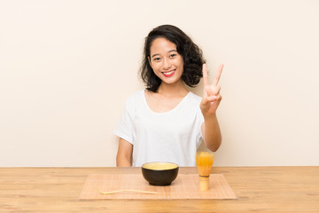 Obraz na płótnie Canvas Young asian girl with tea matcha smiling and showing victory sign