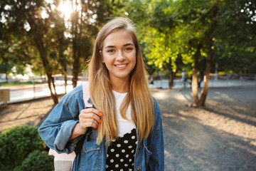 Cheerful young girl walking outside in nature green park.