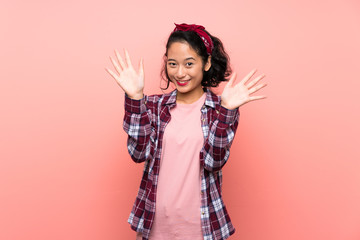 Asian young woman over isolated pink background counting ten with fingers
