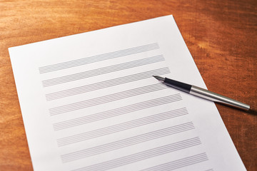 on a wooden table a white sheet of musical notes for recording. inspiration concept.