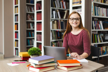 Young female scientist smiling at camera, studying at library