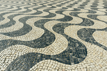 Typical Portuguese black and white stone mosaic calçada pavement in Cascais, Lisbon, Portugal. Also in Copacabana in Rio de Janeiro, Brazil. 