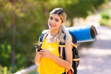 Teenager girl hiking at outdoors sending a message with the mobile