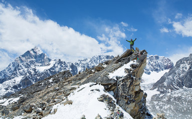 Successful hiker enjoyed at sunny day in the Himalayas mountains, with his hands raised. He reached...