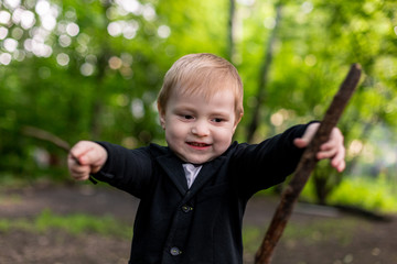 Cute caucasian kid play with a stick in the forest