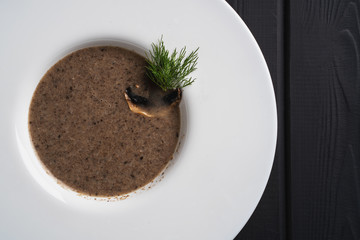 Mushroom cream soup. Traditional dinner with champignon bouillon on black background. Restaurant menu. Fresh vegetarian food.