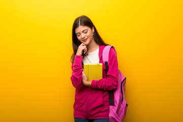 Teenager student girl on vibrant yellow background standing and looking down