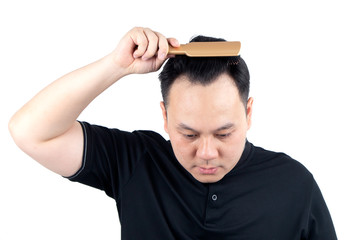 Asian bald man alopecia hand holding comb on bald head isolated on white background. Human hair loss solution and hair transplant concept.