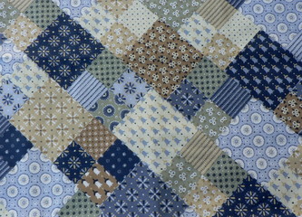 Background of fabric patchwork patterns. Multicolored fabric for needlework and sewing in blue and brown shades.