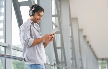Young man in headphones choosing tracks on smartphone