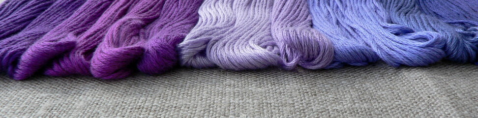 Colored skeins of embroidery floss. Purple and blue color. Macro texture of the fabric linen...