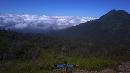 Woman rising hands on the mountain area of Java island, Indonesia, drone shot