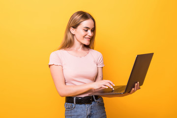 Young pretty woman holding laptop isolated on orange background