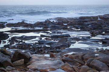 Atlantic Ocean coast in Portugal in the morning. Seascape in blue morning fog. Ocean beach with stones and waves. Empty beach. Rocky coastline. Calm ocean shore. Wild nature concept. 
