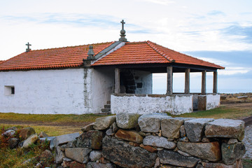 Abandoned ancient church on the Atlantic Ocean coast, Portugal. Medieval catholic church with cross in village. Religious architecture. Small rural white church. Facade of old church. 