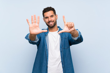 Handsome man over isolated blue background counting seven with fingers