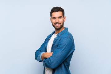 Handsome man over isolated blue background with arms crossed and looking forward