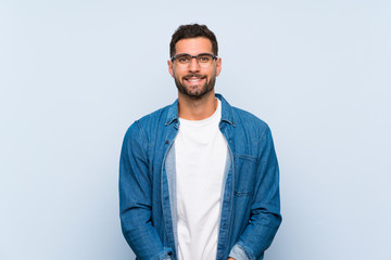 Handsome man over isolated blue background with glasses and happy