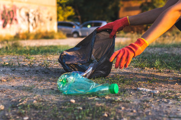 Garbage bottles picked up and thown into a trash bag. Plastic and food waste concept. Clean planet Earth, collect garbage, avoid pollution, save environment.