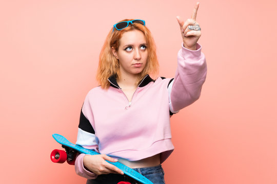 Young skater woman over isolated pink background touching on transparent screen - Powered by Adobe
