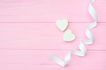 Two white hearts and ribbon on pink wooden background with place for your love text. Flat lay, top view. Valentines Day design