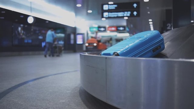 Baggage reclaim at the airport, travellers picking their luggages from the belt after arrival