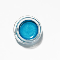 A very pigmented powder of blue eyeshadow on it's package, on a white background