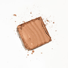 A makeup product, cracked in pieces on a white background