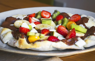 Sweet pizza made of fruits and chocolate spread.