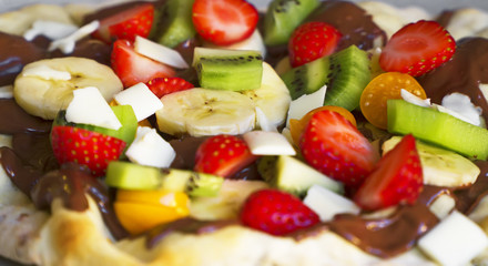 Sweet pizza made of fruits and chocolate spread.