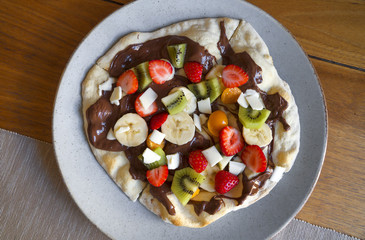 Sweet pizza made of fruits and chocolate spread.