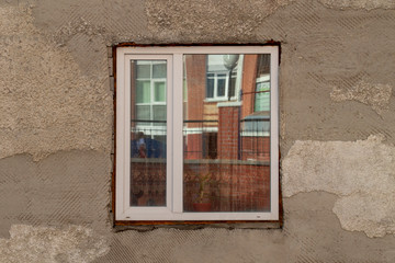 Window with street reflection in an old house with peeling stucco.  Front view.