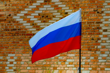 Russian waving flag on a brick wall background with a pattern.  Front view.