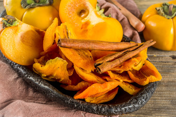 Dried persimmon fruit, with fresh persimmons, on wooden rustic background copy space