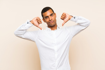 Young handsome brunette man over isolated background showing thumb down