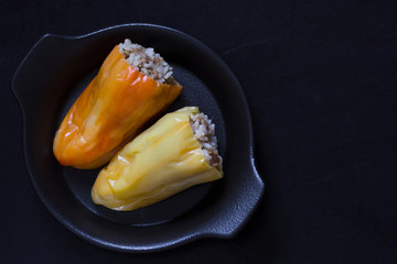 Stuffed pepper with rice and meat on black plate on black background