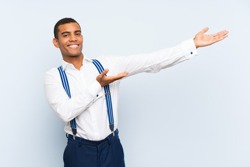 Young handsome brunette man with suspenders over isolated background extending hands to the side...