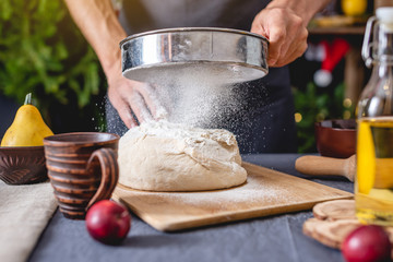 Man chef in a black apron kneads the dough with hands for Christmas baking. Joyful cooking for festive new year table