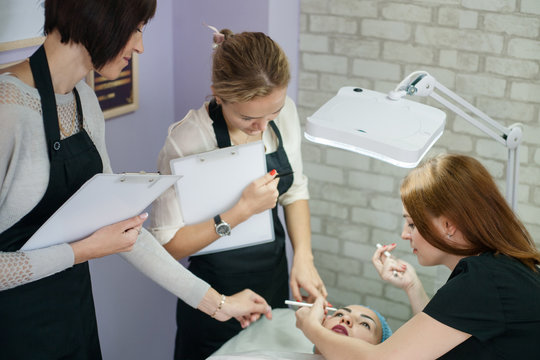 Professional cosmetology courses. Permanent makeup. Female beautician sketching up symmetrical eyebrows.