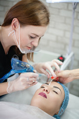 Decorative cosmetology courses. Female beautician using tattoo machine for eyebrow microblading.