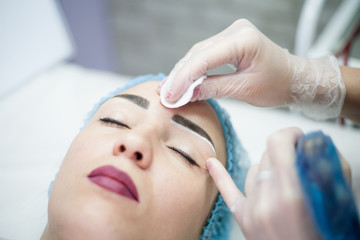 Obraz na płótnie Canvas Decorative cosmetology. Eyebrow design. Closeup portrait of female client enjoying beauty procedure.