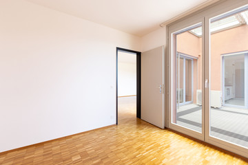 Empty room with white walls and window with balcony