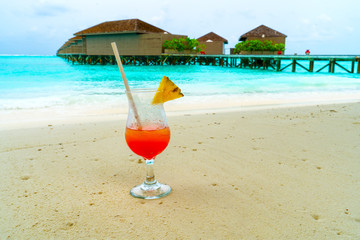 Glass of cocktail is on sandy coral beach, Maldives, The Indian