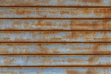 Rusty metal wall covered with cracked blue paint. Texture.